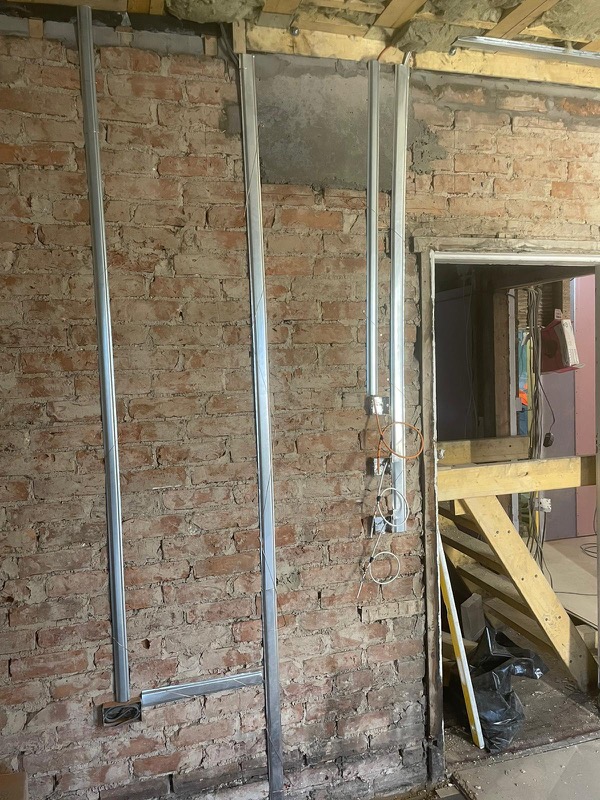 Rewire in progress — new conduit runs on exposed brick during a refurbishment